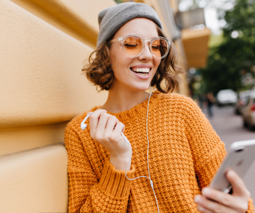 Smiling woman with earphones, watching something on her phone